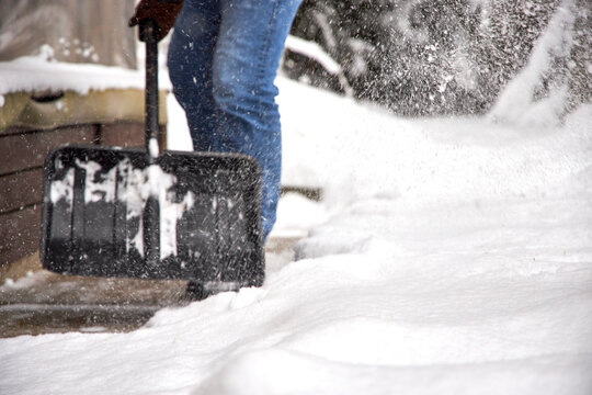 Man shoveling snow in a backyard during winter, clearing a path near a house. Snowy weather, warm clothing, seasonal outdoor work and home maintenance in cold climate