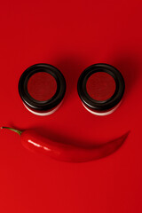 Smiley face made out of sauce jars and red chili pepper on red