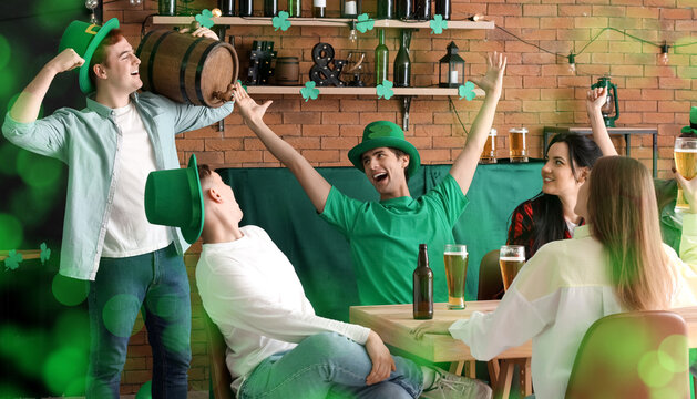 Group of young people with beer celebrating St. Patrick's Day in bar