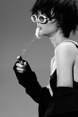 Black and white portrait of a stylish woman smoking with round sunglasses and short hair in monochrome tone