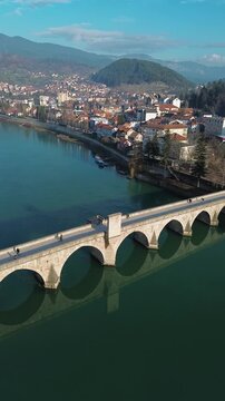Aerial view of the historic Mehmed Pasha Sokolovic Bridge crossing the Drina River in Visegrad, Bosnia and Herzegovina. Timeless Ottoman architecture meets calm river landscape