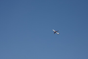 A small airplane flying high in a vast, clear blue sky.