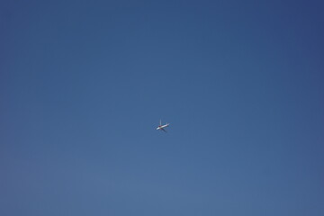A small airplane flying high in a vast, clear blue sky.