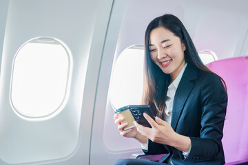  A woman is sitting on an airplane, working and looking at her laptop.