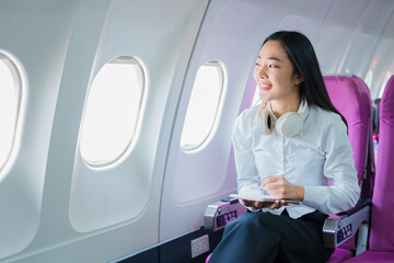 The businesswoman enjoyed her flight by listening to music with wireless headphones and using her smartphone while on the plane.