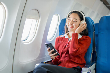  The businesswoman enjoyed her flight by listening to music with wireless headphones and using her smartphone while on the plane.