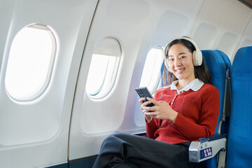  The businesswoman enjoyed her flight by listening to music with wireless headphones and using her smartphone while on the plane.