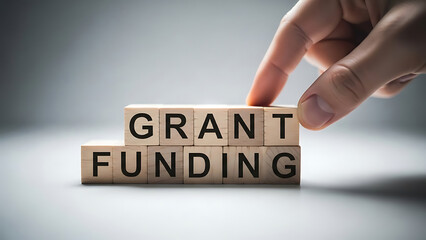 Hand arranging wooden blocks with grant funding text on them