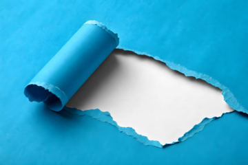 Ripped hole in blue paper with rolled edge isolated on a white or transparent background.