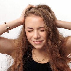 Fototapeta premium Young woman holding her head with a pained expression in a bright indoor setting during daylight hours