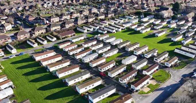 Aerial drone footage of the town of Harrogate in North Yorkshire UK showing a caravan park with rows of static mobile homes surrounded by a British housing estate on a cold day in the winter time