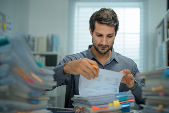 Tired manager grappling with mental fatigue and anxiety, trying to maintain efficiency while handling an overwhelming stack of paperwork and reports.

