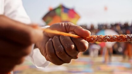 Closeup of hands holding a kite string during a festival.