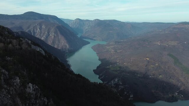 Aerial horizontal view of rocky cliffs and forested slopes in Tara National Park overlooking the Drina River and Perucac Lake during a snowless winter. Scenic natural landscape of western Serbia