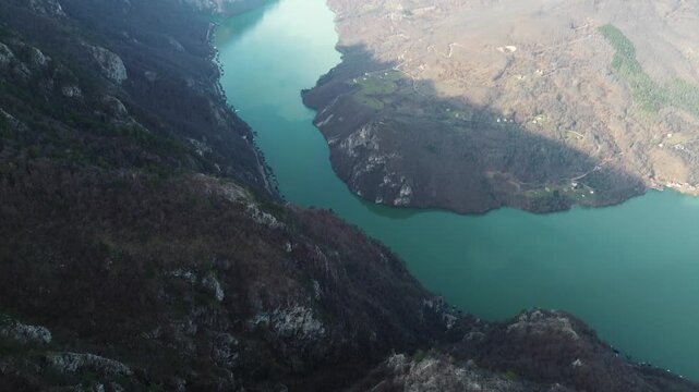 Aerial horizontal view of rocky cliffs and forested slopes in Tara National Park overlooking the Drina River and Perucac Lake during a snowless winter. Scenic natural landscape of western Serbia