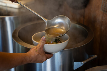 Vietnamese pho bo soup preparation with hot beef broth pouring