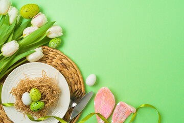 Easter festive table setting with easter eggs decoration and white tulips flowers on green background. Top view , flat lay