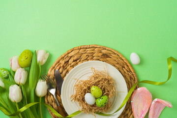 Easter festive table setting with easter eggs decoration and white tulips flowers on green background. Top view , flat lay