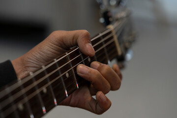 Close-up of a musician&rsquo;s hand pressing strings on an electric guitar fretboard, showing technique, practice and music skill.