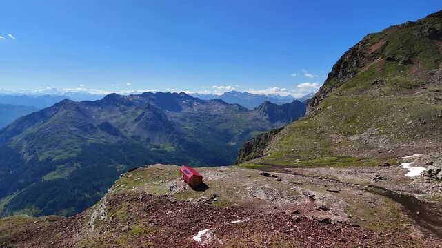Aerial drone view of the mountain shelter Bivacco Piano della Parete in Switzerland. Surrounded by mountains and a waterfall, silence and serenity prevail. Outdoor adventure and a traveling lifestyle.