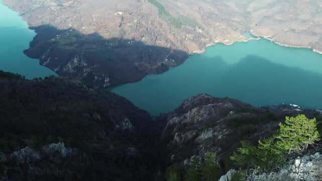 Aerial horizontal view of rocky cliffs and forested slopes in Tara National Park overlooking the Drina River and Perucac Lake during a snowless winter. Scenic natural landscape of western Serbia