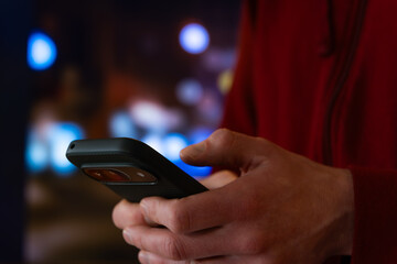 Smartphone In Hand On City Street At Night, Mobile Texting And Messaging With Bokeh Lights, Technology Communication For Urban Travel And Lifestyle