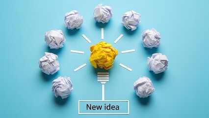 Concept of developing a brilliant new idea overcoming many failed drafts represented by crumpled white papers surrounding a central yellow success lightbulb on blue