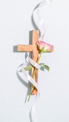 Spiritual Vertical Composition with Wooden Cross, Pink Rose, and Elegant White Ribbon. Minimalist Aesthetic Concept of Faith, Grace, and Love for Christian Branding, Easter, or Sympathy Designs