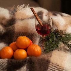 Warm drink with cinnamon stick and tangerines on cozy blanket  