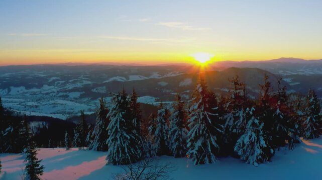 An extraordinary valley with hills and mountains covered with fir forests against the backdrop of a bright fiery sunset