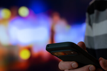 Smartphone In Hand In City Night, Mobile Phone Bokeh Texting And Communication For Urban Travel, Messaging, Browsing, And On The Go Lifestyle