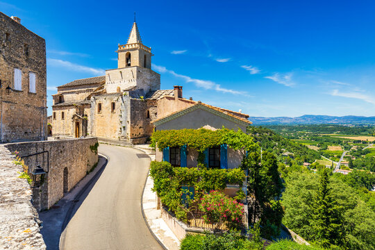 View of Venasque village with old church Notre Dame de Vie to landscape of Luberons, Provence, France. Beautiful Church and houses in the town of Venasque, Provence, France.