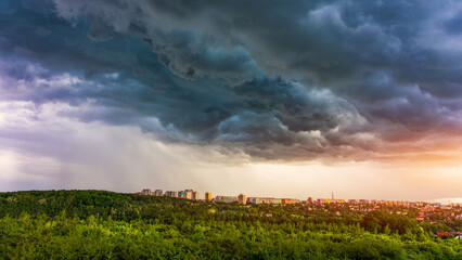 Dark clouds loom over a Prague city skyline at sunset, contrasting with green trees below. Dramatic cloudy sky over Prague city skyline during sunset, blending nature and urban life. Prague, Czechia.