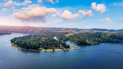 View of Slapy in Czechia showcasing the peaceful lake and surrounding lush greenery on a sunny day. Slapy reveals a tranquil lake surrounded by hills, dotted with boats and greenery. Slapy, Czechia.