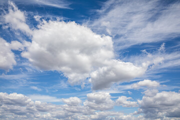 Soft white clouds float across a clear blue sky, creating a serene atmosphere during a sunny afternoon. The scene invites a sense of calm and peace in nature.