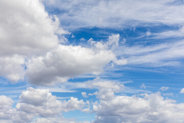 Soft white clouds float across a clear blue sky, creating a serene atmosphere during a sunny afternoon. The scene invites a sense of calm and peace in nature.