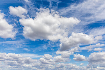 Soft white clouds float across a clear blue sky, creating a serene atmosphere during a sunny afternoon. The scene invites a sense of calm and peace in nature.