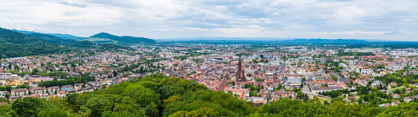 Germany, XXL aerial panorama view of freiburg im breisgau city houses skyline surrounding downtown minster cathedral church marketplace old town tourism destination above tree tops