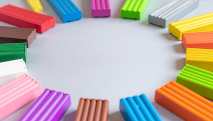 Colorful plasticine bars in a circle on grey background with copy space