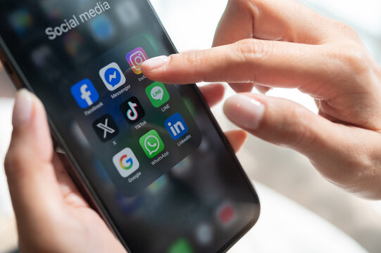 Bangkkok, THAILAND - January 2nd, 2026: Womans Hands using Iphone with icons of social media on screen consist of facebook, instagram, X, Tiktok, Line, WhatsApp and Linkedin