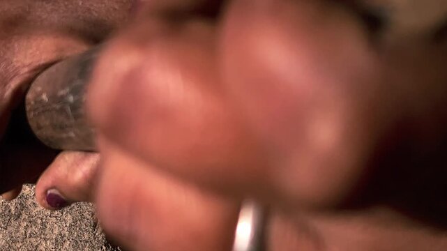 An Indian village woman grinding black gram lentils on a hand-driven stone mill showcases traditional agriculture-based lifestyles, homemade food culture, and timeless rural craftsmanship.