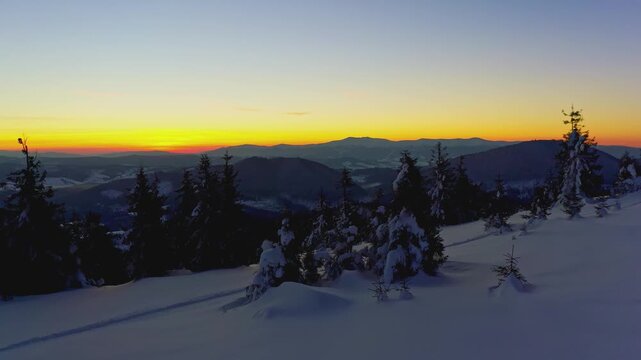 An extraordinary valley with hills and mountains covered with fir forests against the backdrop of a bright fiery sunset