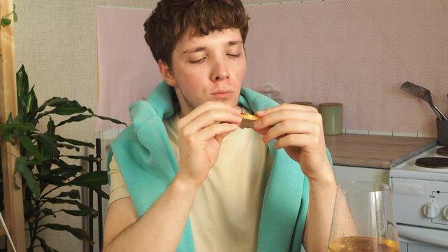 A young attractive man is having breakfast in his kitchen early in the morning.