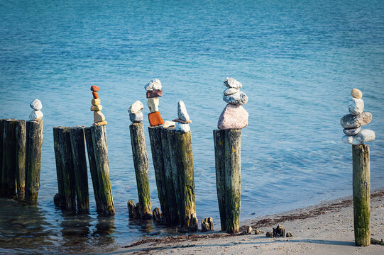Several colorful stone towers on wooden stilts on the Baltic Sea beach.