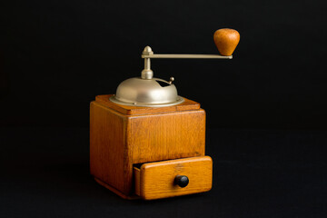 Classic wooden coffee grinder with a metal handle and an open drawer, set against a dark, minimalist background. Captures the essence of traditional coffee preparation.