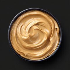 Creamy peanut butter in a bowl on black background  
