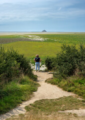 Fototapeta premium Person on Path Overlooking Distant Island Mont-Saint-Michel