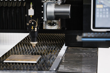 CNC fiber laser cutting head positioned above sheet metal on lamella support table with slats for precise contour cutting