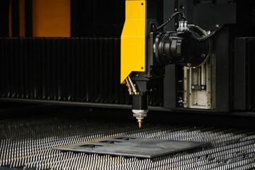 fiber laser cutting machine head with nozzle precisely cutting contours in sheet metal plate for high-precision part fabrication