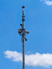 Industrial telecommunication tower pole with transmitters against a clear blue sky. Commercial asset for 5G, networking, and technology themes.